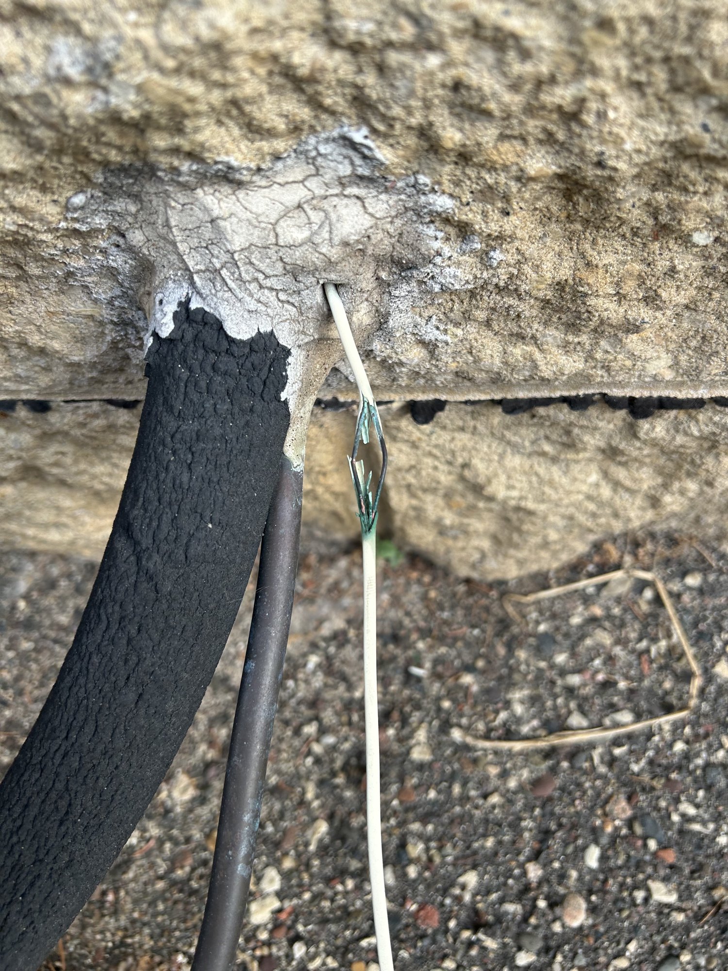 Sun-damaged thermostat wire along the line set at the condenser — the cracked jacket shorts out when it rains or when bare conductors touch.