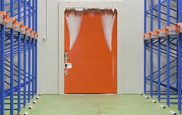Polar strip curtains at a forklift entrance hold back the cold spill — frost at the opening shows how hard the doorway works.